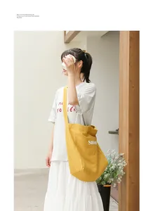 Detailed view of yellow canvas tote bag worn by model in a minimalist setting