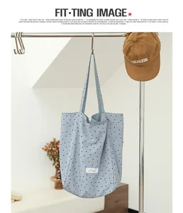 Detailed close-up of a blue polka dot nylon tote bag hanging on a metal garment rack
