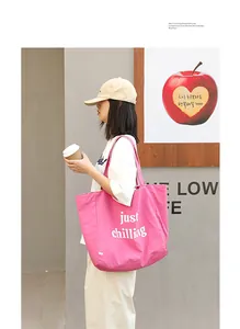 Stylish pink nylon tote bag featuring a 'just chilling' letter print shown on a model