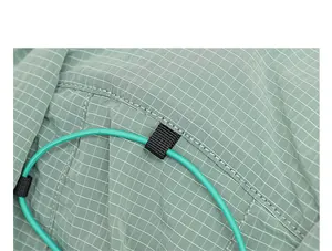 Close-up detail of green plaid nylon fabric and drawstring on a stylish backpack