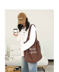 Modelo asiática luciendo un bolso tote de lona de algodón marrón con cordón ajustable.
