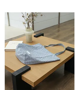 Detail of a Japanese style light blue polka dot nylon tote bag on a wooden table.