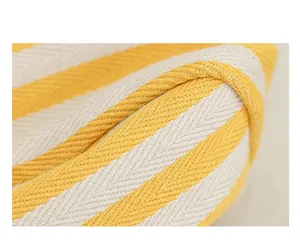 Detalle de bolso de lona a rayas amarillas y blancas con textura de tejido de espiga