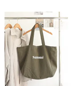 Japanese style large olive green linen tote bag with 'Salomé' print hanging on a clothing rack