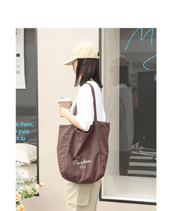 Young woman carrying a brown nylon tote bag with 'Our fave' letter print