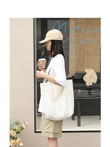Close-up of a Japanese-style white canvas tote bag with black polka dot patterns.