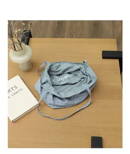 A detailed top-down view of a light blue polka dot nylon tote bag on a wooden table
