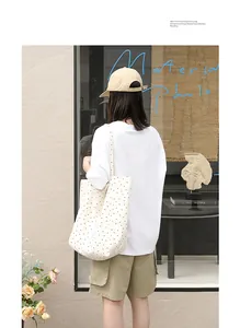 Artistic white canvas tote bag with black polka dots in a stylish lifestyle scene