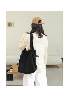 Model carrying a large black drawstring tote bag in a minimalist lifestyle setting