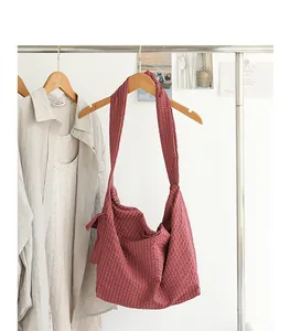 Red checkered Japanese style messenger bag with knotted strap shown on white clothing rack
