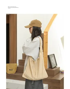 Model wearing a stylish beige suede-like drawstring hobo bag in a modern interior setting