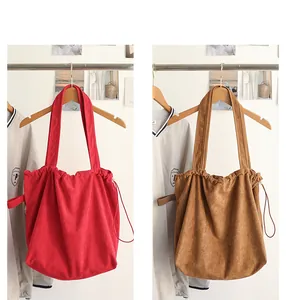 Casual suede drawstring tote bag in red and brown colors hanging on hangers