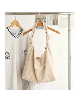 Dettaglio della borsa hobo in finta pelle scamosciata beige con spalline annodate.