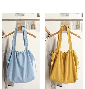 Detailed close-up of suede-like drawstring tote bags in light blue and mustard yellow