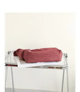 Close-up of Japanese style red plaid canvas crossbody bag with decorative knotted strap.