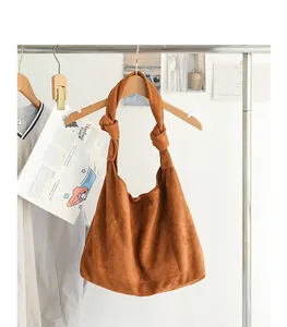 Primo piano di una borsa hobo in pelle scamosciata marrone con tracolla annodata