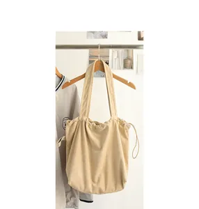 Close-up detail of a minimalist beige suede-like drawstring tote bag with Japanese aesthetic