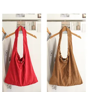 Red and tan suede drawstring shoulder bags hanging on a display rack.