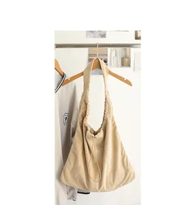 Detail of a casual beige suede hobo bag with drawstring pleated design on a hanger