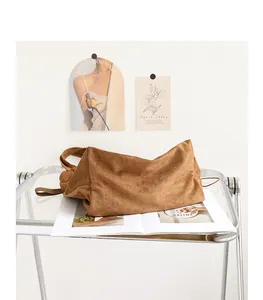 Detailed view of caramel suede drawstring tote bag on aesthetic acrylic table