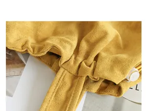 Close-up of the yellow suede fabric texture and drawstring pleated detail of the tote bag.