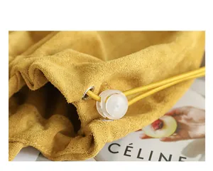 Close-up of yellow suede bag drawstring with metallic eyelet and plastic toggle
