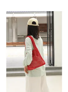 Detail of a red handmade cotton woven mesh shoulder bag shown on a model back view
