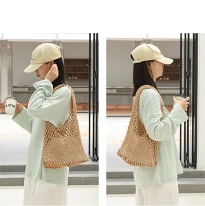 Side view of woman carrying a beige woven cotton mesh shoulder bag with inner pouch