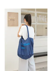 Bolso tote grande de lona azul con estampado de letras en un entorno urbano real