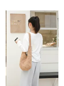 Model draagt een handgemaakte beige gehaakte schoudertas met opengewerkt ontwerp.