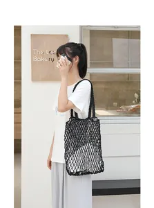 Macro view of black woven mesh beach bag carried by a model in lifestyle setting