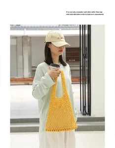 Detail of a stylish yellow woven cotton mesh shoulder bag carried by a model in casual attire