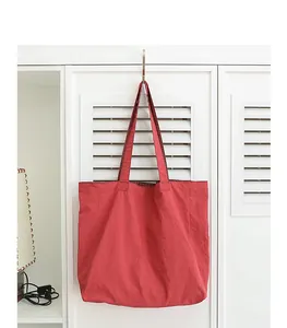 Vista detallada de un bolso tote de nailon rojo vibrante colgado de un gancho blanco