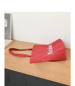 Detalle del bolso de lona rojo que muestra el estampado Miracle blanco en el lateral