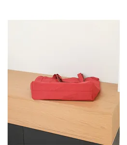 Vista detallada del fondo de un bolso tote de nailon rojo informal sobre madera