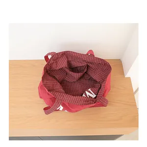 Vista interior de un bolso tote rojo informal con forro de cuadros y compartimento