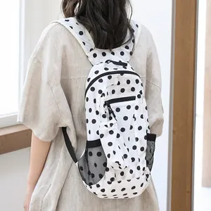Elegante mochila de nailon para mujer con lunares negros clásicos sobre fondo blanco