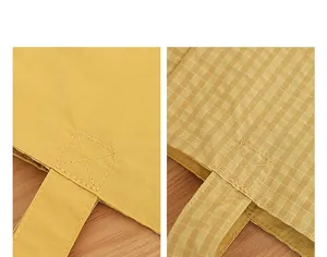 Detalle de costuras reforzadas en bolso tote de nylon amarillo liso y a cuadros
