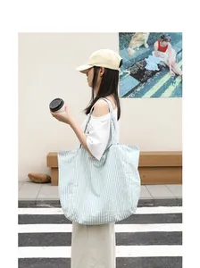 Casual light blue striped nylon tote bag carried by a model in a trendy street setting