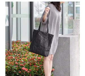 Detailed view of the unique crinkled texture on a black vintage minimalist DuPont paper tote bag