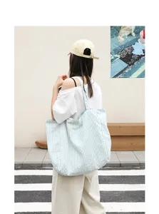Detailed back view of a casual light blue and white striped nylon tote bag carried by a model