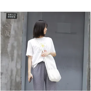 Modelo llevando un bolso de hombro de lona de malla blanca en una escena callejera