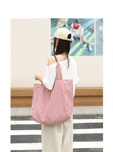 Casual red and white striped nylon tote bag shown in a lifestyle street setting.