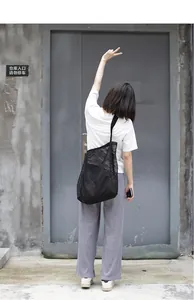 Vista trasera de una mujer con un gran bolso de malla negra en un entorno urbano