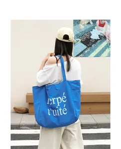 Detailed close-up view of the blue nylon tote bag with stylish white letter print