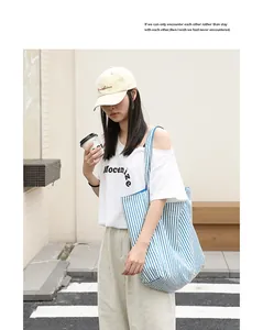 Asian model showing the blue and white striped nylon tote bag in a street lifestyle setting