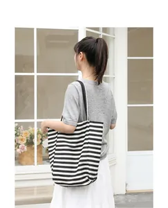 Rear view of model carrying a stylish black and white striped canvas tote bag