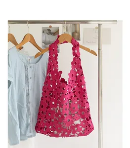 Close-up detail of fuchsia pink floral lace crochet shoulder bag hanging on a wooden hanger