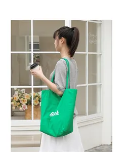 Bolso tote de nailon verde vibrante con letras blancas, llevado por modelo