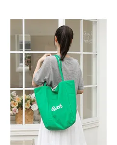 Bolso tote de nailon verde moderno con letras Belch blancas llevado por una modelo.